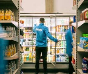 man stacks shelf in zapp blue jumper groceries